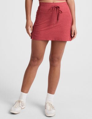 red high-waisted mini athletic skirt with a drawstring at waistband and built-in shorts with pockets.