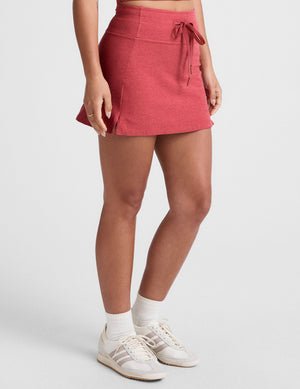red high-waisted mini athletic skirt with a drawstring at waistband and built-in shorts with pockets.