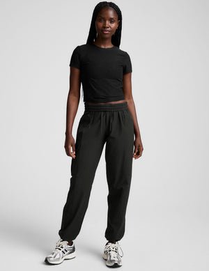 model wearing a black t-shirt and black cargo style pants on a white background.