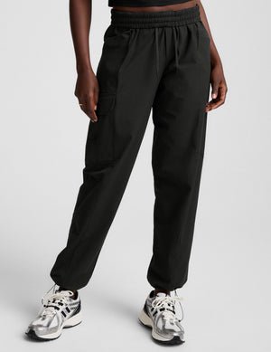 model wearing a black t-shirt and black cargo style pants on a white background.