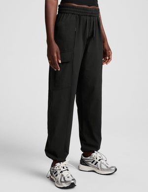 model wearing a black t-shirt and black cargo style pants on a white background.