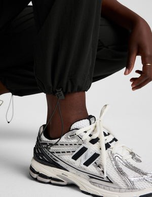 model wearing a black t-shirt and black cargo style pants on a white background.