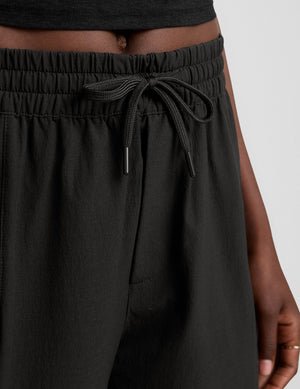 model wearing a black t-shirt and black cargo style pants on a white background.